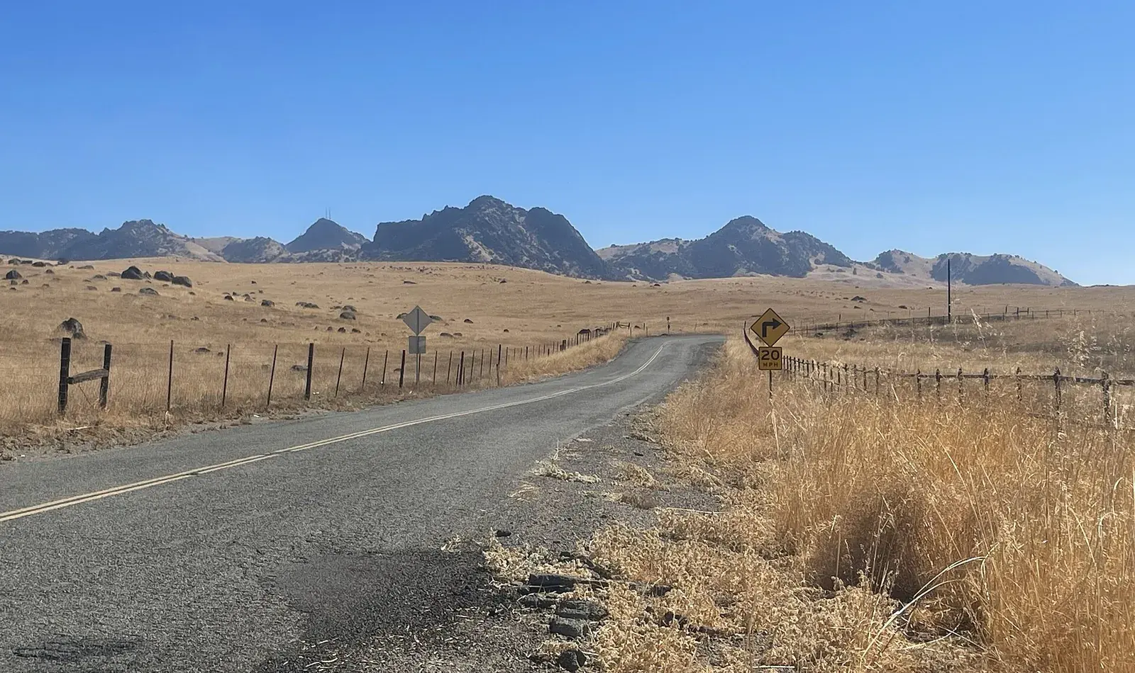 Country road through dry summer grass toward the Sutter Buttes