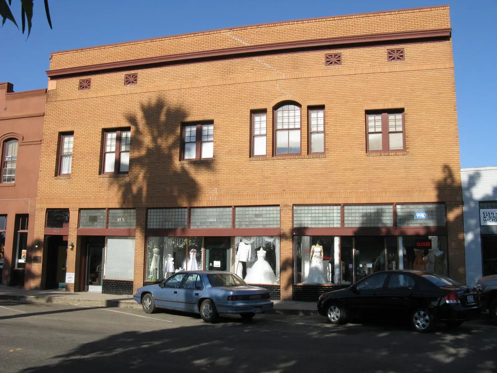 Two-story tan brick Odd Fellows building with arched upper windows and shopfronts on Broadway in downtown Live Oak